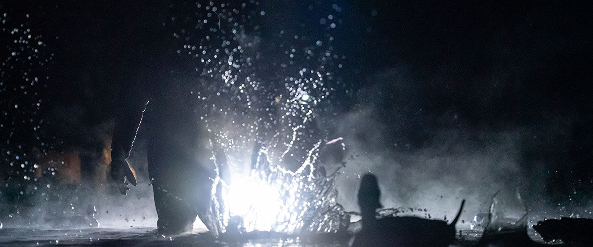 light illuminating a water splash, hunter, and duck decoys